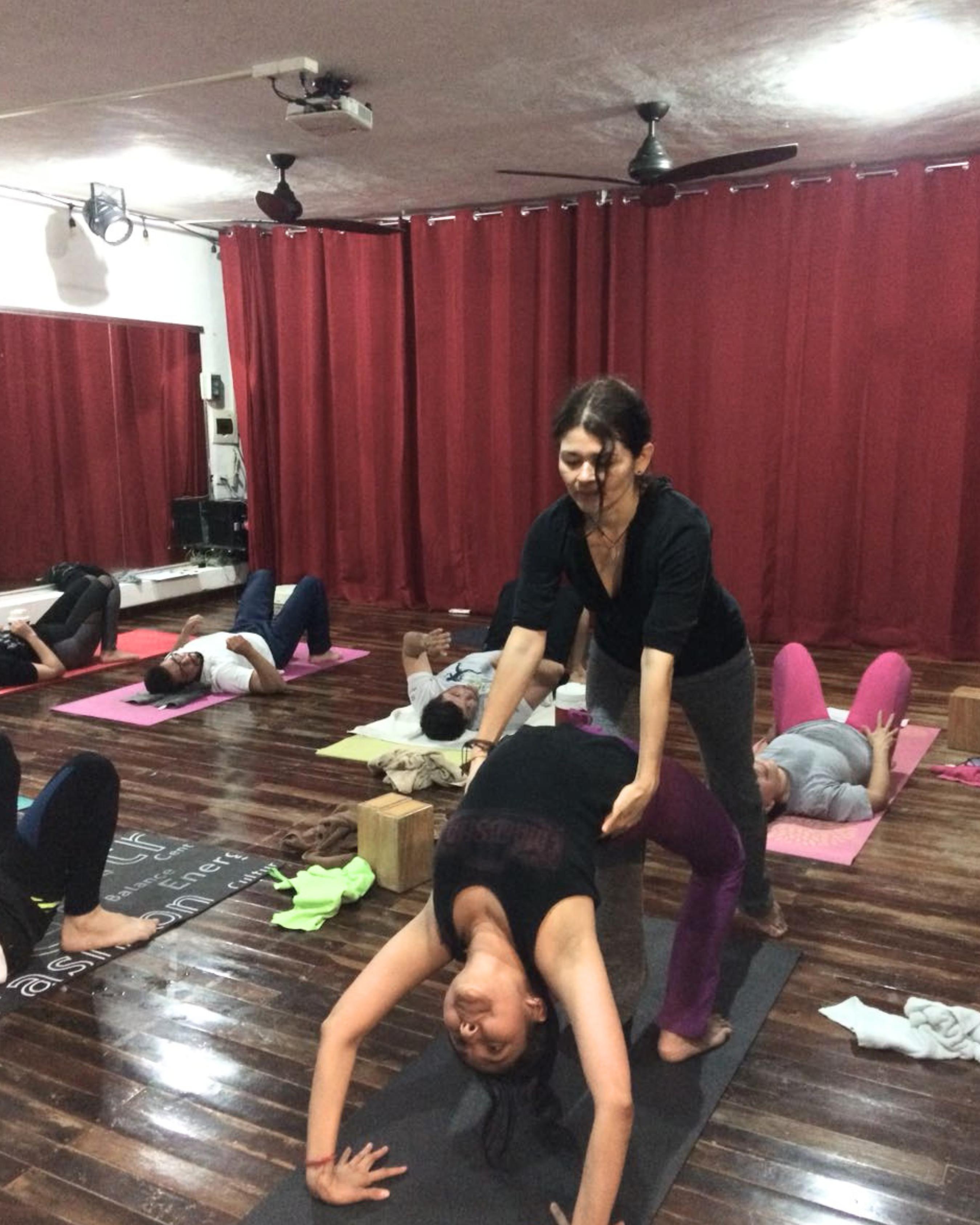 Karla Gómez enseñando y ajustando a una alumna durante una clase en el Shala